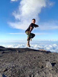 Side view of man standing on mountain against sky