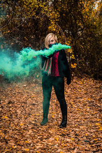 Full length of woman standing amidst leaves in forest