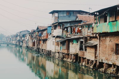 Residential buildings by river against sky