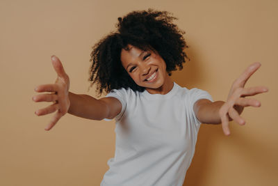 Portrait of smiling young woman standing against gray background