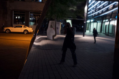 People walking on sidewalk in city at night