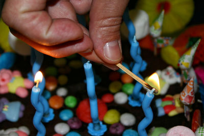 Close-up of person burning candles on cake