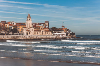 Buildings by sea against sky in city