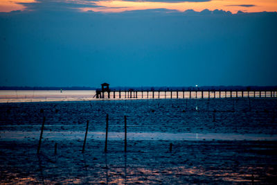 Silhouette people on beach against sky during sunset