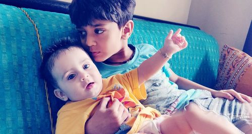 Cute siblings sitting on sofa at home