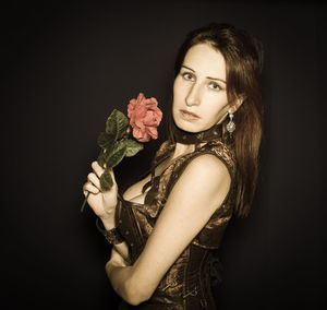 Portrait of young woman wearing mask against black background