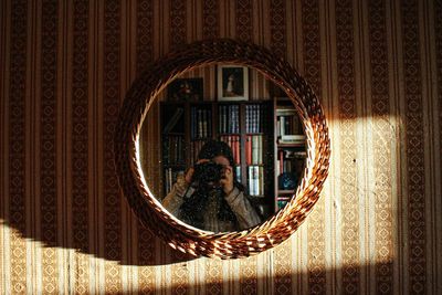 Reflection of man photographing through window