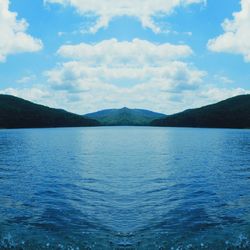 Scenic view of sea and mountains against blue sky