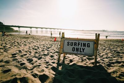 Information sign on beach against clear sky