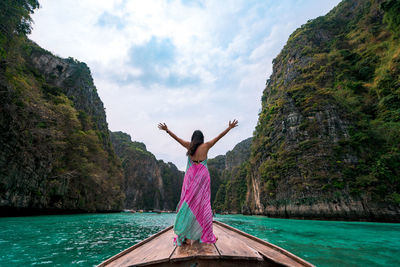 Rear view of man jumping on sea against mountain