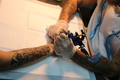 High angle view of artist making tattoo on hand