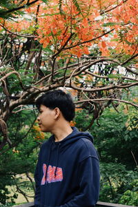 Low angle view of boy standing by tree