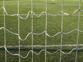 Hang bended white soccer net in soccer football gate. grass and white painted line on playground