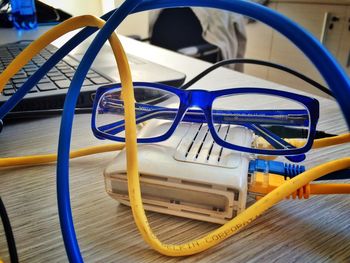 Close up view of eyeglasses among yellow and blue modem cables 