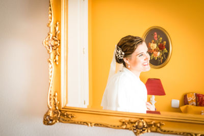 Portrait of smiling young woman against wall