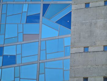 Low angle view of glass building against blue sky