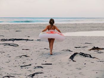 Full length rear view of woman standing on beach