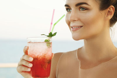 Close-up of woman holding drink against white background