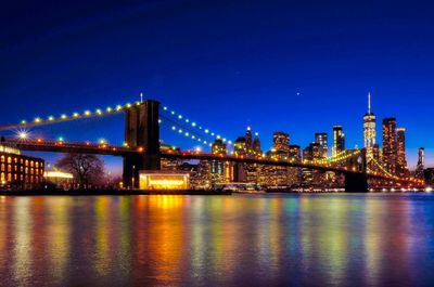 Illuminated bridge over river at night