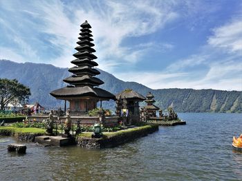 Traditional building by lake against sky