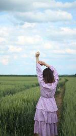Rear view of woman standing on field against sky