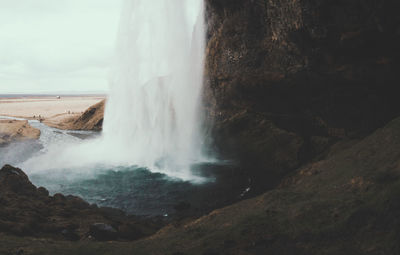 Waterfall on cliff against sky