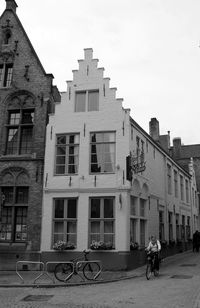 People riding bicycle on street against buildings in city