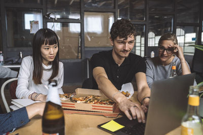 Smiling colleagues with pizza working at workplace