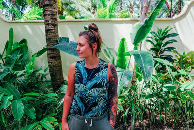 Young woman standing against plants