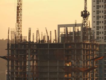 Cranes at construction site against sky