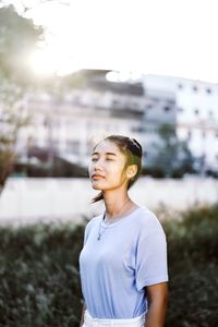 Portrait of smiling woman standing against city in background