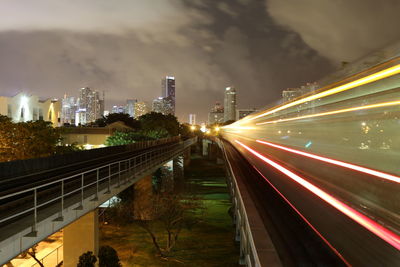 Light trails on road in city against sky at night