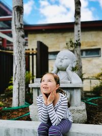 Cute girl looking up while standing against sculpture