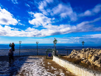 Mother and son standing outdoors during winter against sky