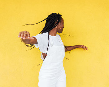 Midsection of woman standing against yellow wall