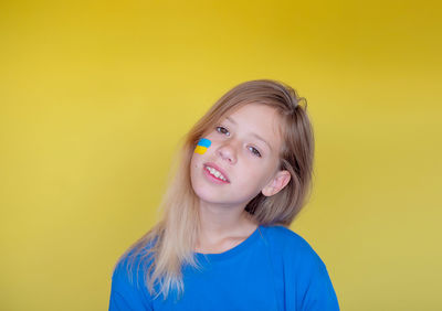 Portrait of young woman against yellow background