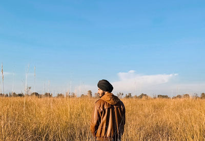 Rear view of man standing on field against sky