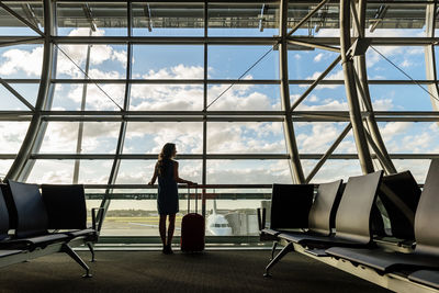 Woman standing by window at airport