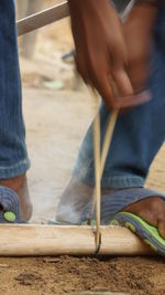 Low section of worker tying rope on wooden post