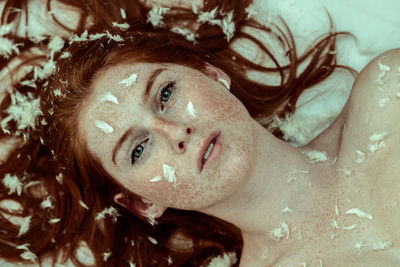 Close-up portrait of young woman with freckles on face