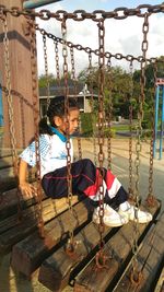 Boy sitting on swing at playground