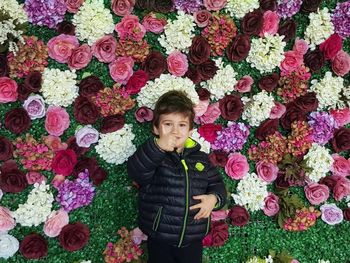 Portrait of boy standing against flowering plants