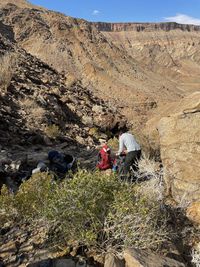 People on rock by mountains