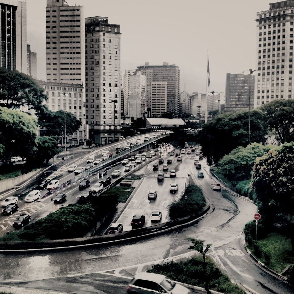 transportation, city, building exterior, car, architecture, land vehicle, built structure, mode of transport, road, traffic, street, high angle view, city life, city street, on the move, road marking, tree, cityscape, skyscraper, the way forward