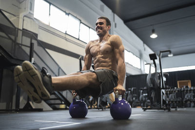 Smiling male athlete exercising with kettle bell in gym