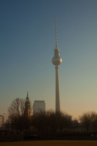 Communications tower in city against clear sky