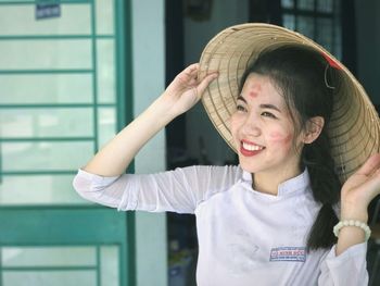 Portrait of smiling young woman standing against building