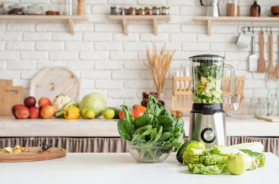 Healthy eating, dieting concept. home kitchen with a table with green vegetables and blender