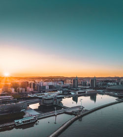 High angle view of river by buildings against sky during sunset