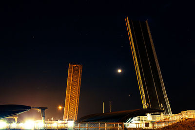 Low angle view of illuminated bridge against sky at night